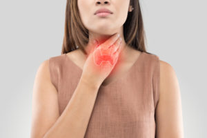 woman holding her throat where the thyroid is