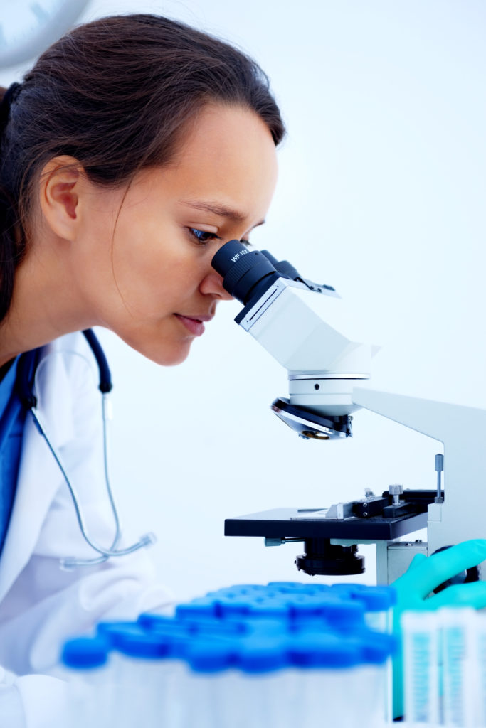 lab technician looking through microscope