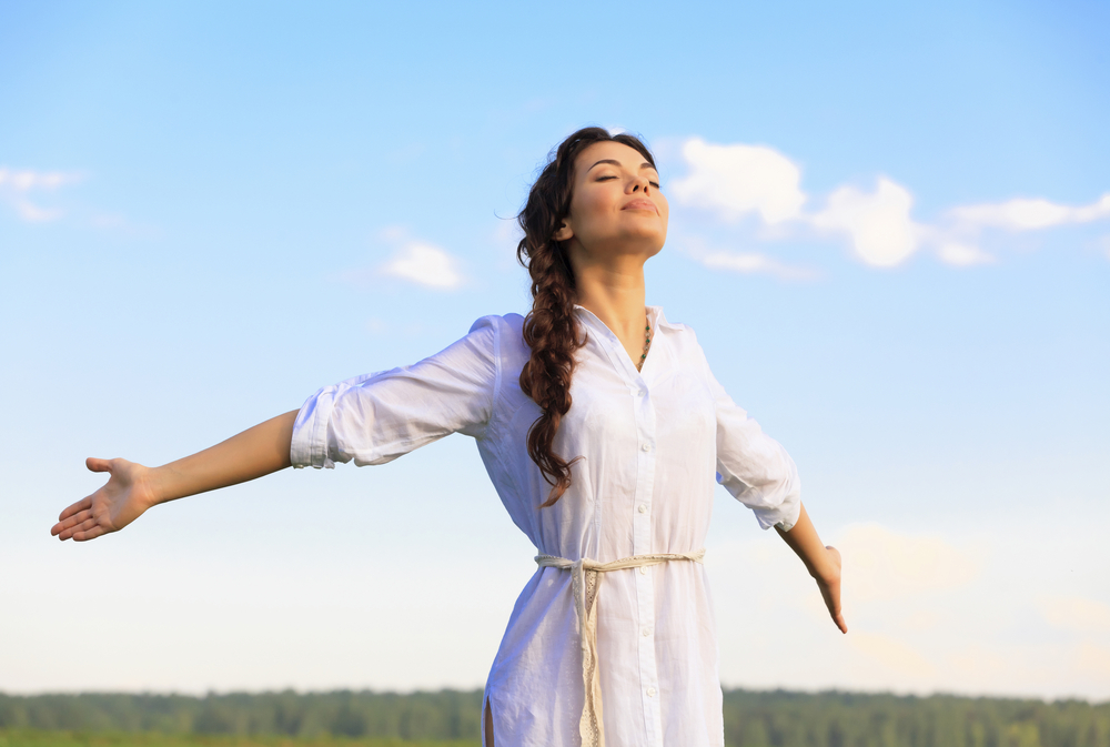 woman smiling with outstretched arms in a field