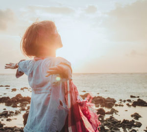 woman stretching out arms at sunrise.