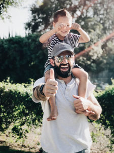 happy man holding a child on his shoulders