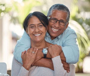 Portrait, elderly and couple bonding on a patio at home, hug, laugh and relax outdoors together. Love, retirement and happy seniors enjoying their relationship and bond, free time and fresh air