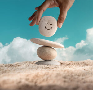 concept of hormone balance with a rock on top of other rocks and a happy face painted on it