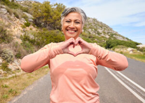 Senior woman, heart hands in front, outside