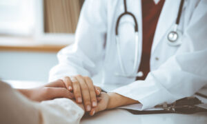 Hands of unknown woman-doctor reassuring her female patient, close-up.