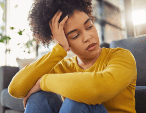 fatigued young woman with PCOS, head in hands