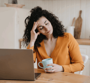 Woman feeling exhausted with coffee and laptop – hormone imbalance fatigue